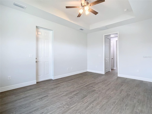 spare room featuring hardwood / wood-style floors, a tray ceiling, and ceiling fan