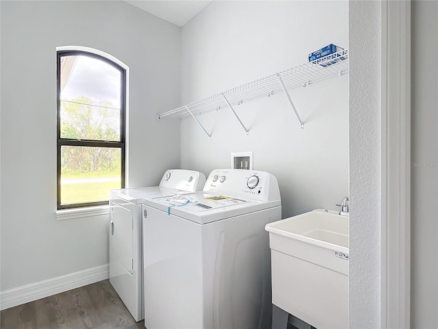 washroom with washing machine and dryer, sink, and hardwood / wood-style flooring