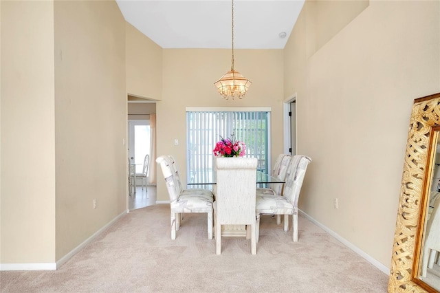 carpeted dining space with a high ceiling and an inviting chandelier