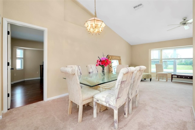 dining room with ceiling fan with notable chandelier, light colored carpet, and lofted ceiling