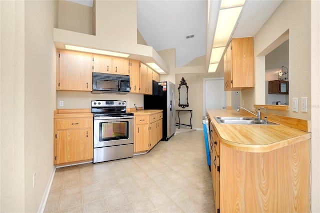 kitchen featuring light brown cabinets, sink, stainless steel appliances, and vaulted ceiling