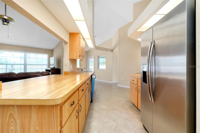 kitchen featuring butcher block countertops, stainless steel fridge, light brown cabinets, and vaulted ceiling