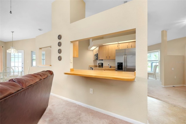 kitchen with kitchen peninsula, appliances with stainless steel finishes, light colored carpet, and hanging light fixtures