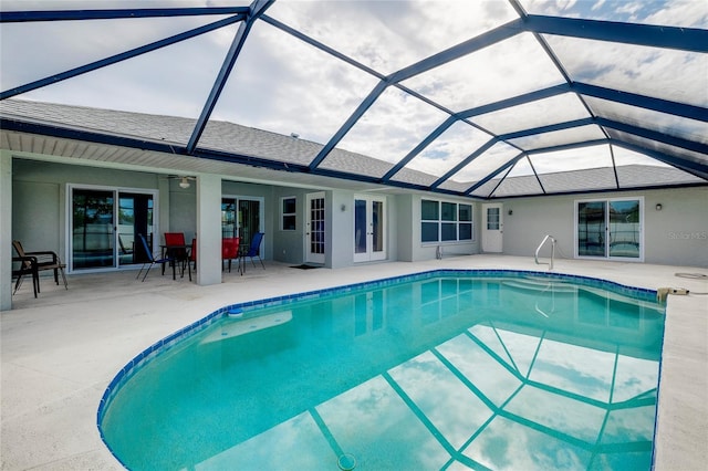 view of swimming pool featuring glass enclosure, ceiling fan, and a patio