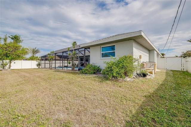 rear view of property with a lanai, a yard, and a fenced in pool