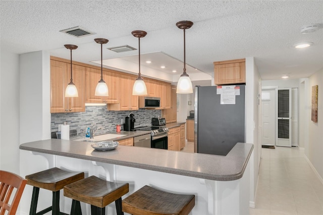 kitchen with kitchen peninsula, appliances with stainless steel finishes, backsplash, a kitchen breakfast bar, and light brown cabinetry