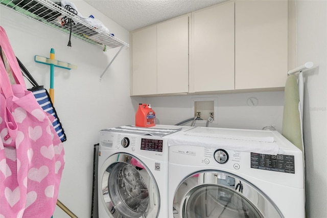 laundry room with cabinets, a textured ceiling, and washer and clothes dryer