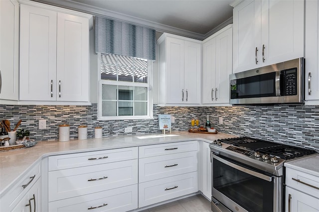 kitchen with tasteful backsplash, white cabinets, and appliances with stainless steel finishes