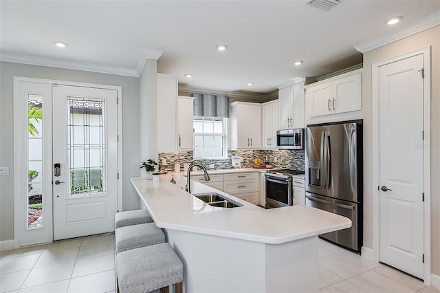 kitchen featuring kitchen peninsula, appliances with stainless steel finishes, a breakfast bar, sink, and white cabinetry