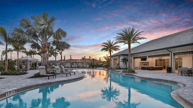 pool at dusk featuring a patio