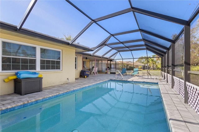 view of pool featuring glass enclosure, ceiling fan, and a patio