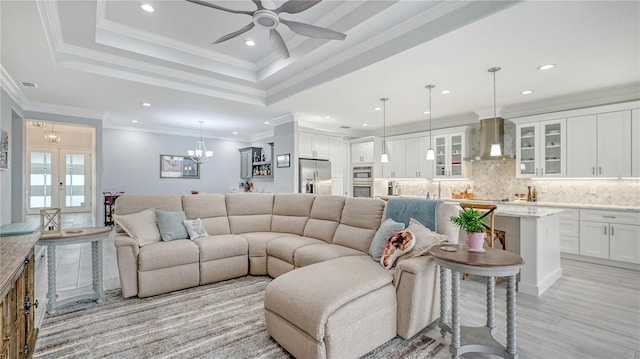 living room featuring a tray ceiling, light hardwood / wood-style flooring, ceiling fan, and crown molding