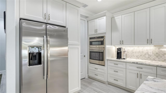 kitchen with white cabinets, decorative backsplash, ornamental molding, light stone counters, and stainless steel appliances