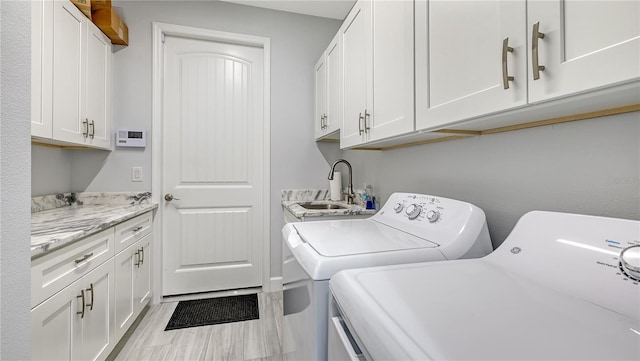 clothes washing area with cabinets, independent washer and dryer, and sink