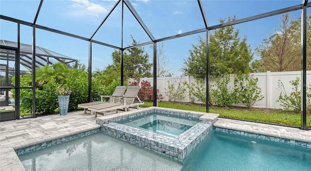 view of swimming pool with an in ground hot tub, glass enclosure, and a patio area