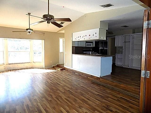 kitchen featuring black fridge, white cabinetry, dark wood-type flooring, and vaulted ceiling