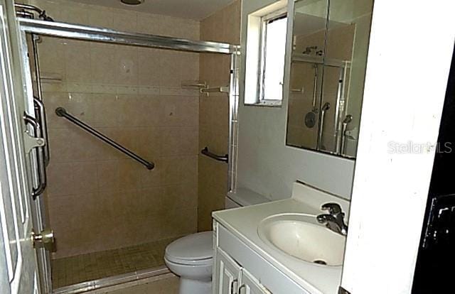 bathroom with vanity, toilet, and tiled shower