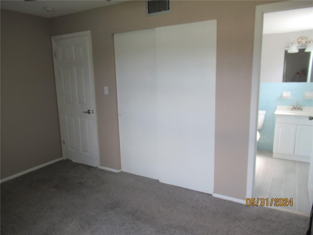 unfurnished bedroom with light carpet, ensuite bathroom, and sink