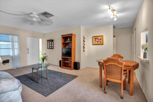 living room with ceiling fan, light colored carpet, and a textured ceiling