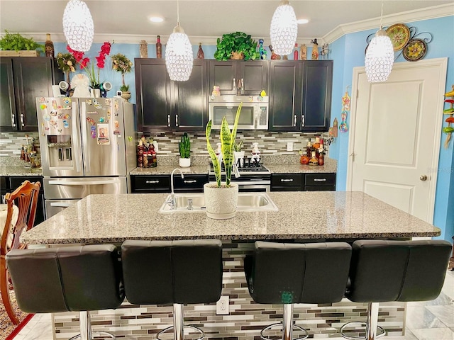 kitchen featuring stainless steel appliances, hanging light fixtures, and an island with sink