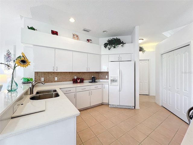 kitchen with white fridge with ice dispenser, sink, light tile patterned floors, backsplash, and white cabinets