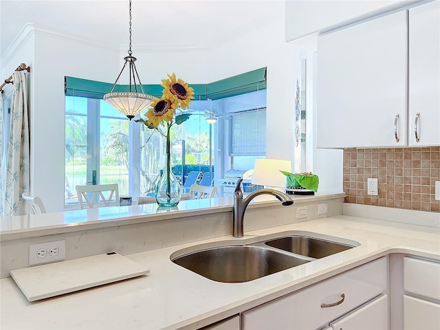 kitchen featuring white cabinets, decorative light fixtures, ornamental molding, and sink