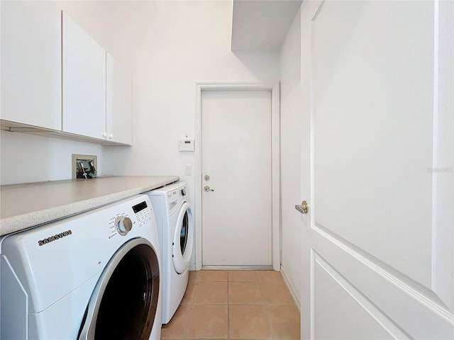 washroom featuring cabinets, light tile patterned floors, and washing machine and clothes dryer