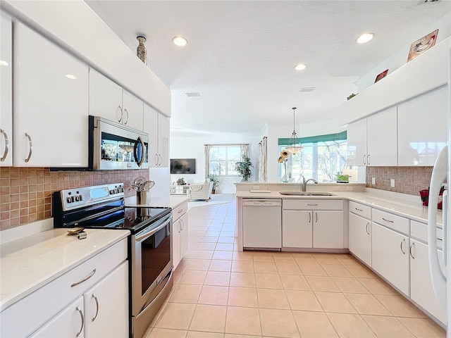 kitchen with tasteful backsplash, stainless steel appliances, white cabinets, hanging light fixtures, and light tile patterned flooring