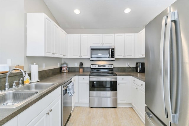 kitchen with appliances with stainless steel finishes, light hardwood / wood-style flooring, white cabinetry, and sink