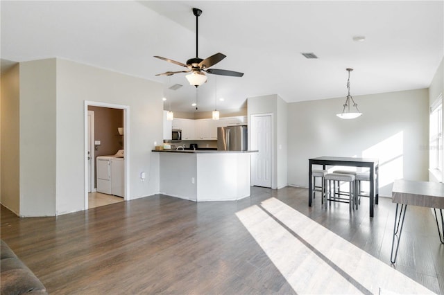 kitchen featuring white cabinetry, dark wood-type flooring, kitchen peninsula, washer and dryer, and appliances with stainless steel finishes