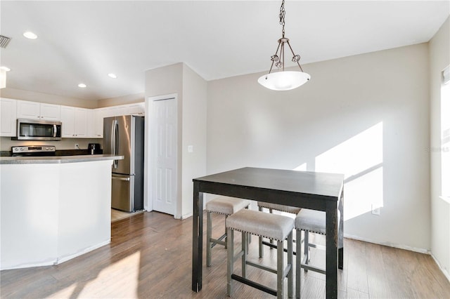 kitchen featuring white cabinets, pendant lighting, light wood-type flooring, and appliances with stainless steel finishes