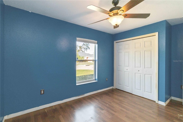 unfurnished bedroom featuring ceiling fan, dark hardwood / wood-style flooring, and a closet