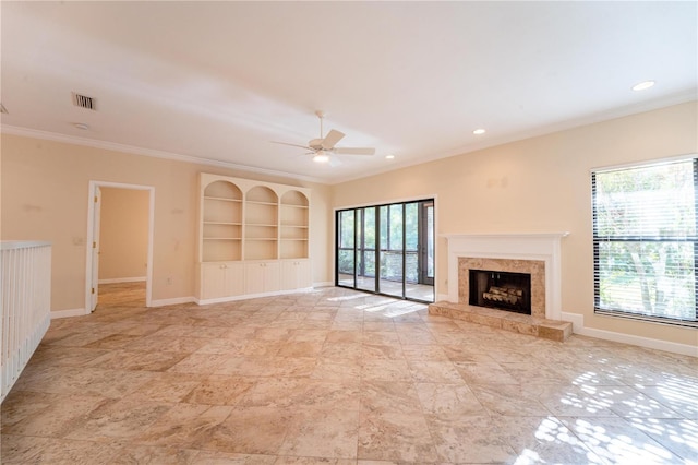 unfurnished living room with a high end fireplace, built in features, plenty of natural light, and crown molding