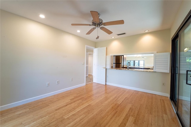 unfurnished living room featuring light wood-type flooring, ceiling fan, and sink