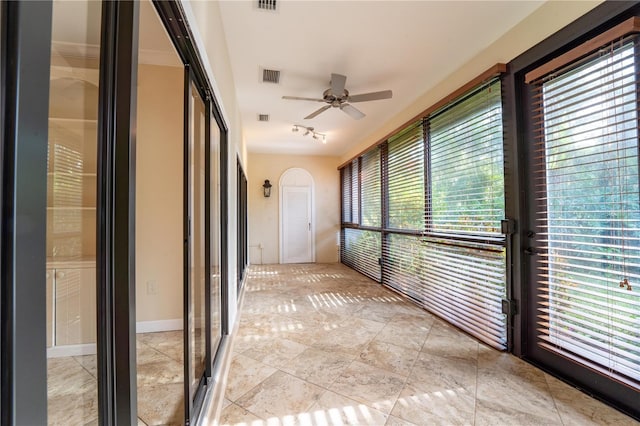 unfurnished sunroom with ceiling fan