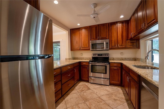 kitchen featuring ceiling fan, sink, light stone counters, kitchen peninsula, and appliances with stainless steel finishes