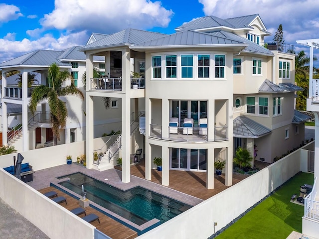 back of house with a balcony, a fenced in pool, and a patio