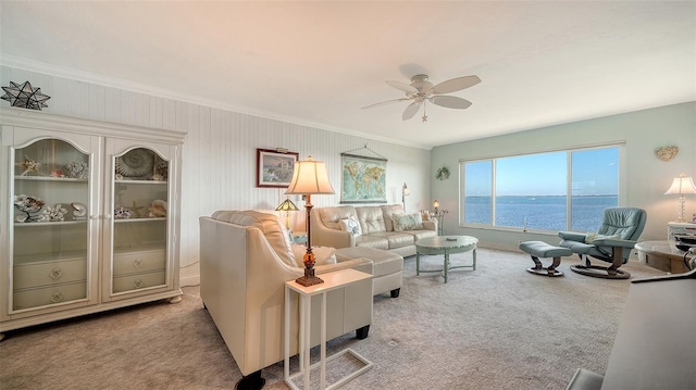 living room with light carpet, crown molding, a water view, and ceiling fan