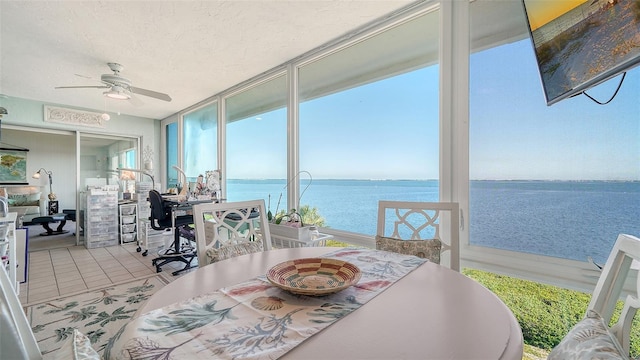 sunroom / solarium featuring ceiling fan and a water view