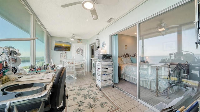 bedroom with ceiling fan, a closet, light tile patterned flooring, and a textured ceiling