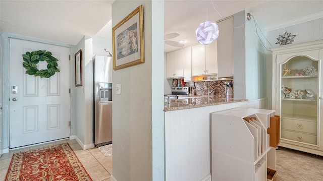 interior space with stainless steel fridge, light stone counters, light tile patterned floors, white cabinets, and hanging light fixtures