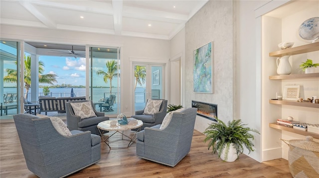 interior space with beamed ceiling, a water view, coffered ceiling, and a tiled fireplace