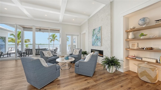 living room with a fireplace, a water view, light hardwood / wood-style flooring, and plenty of natural light