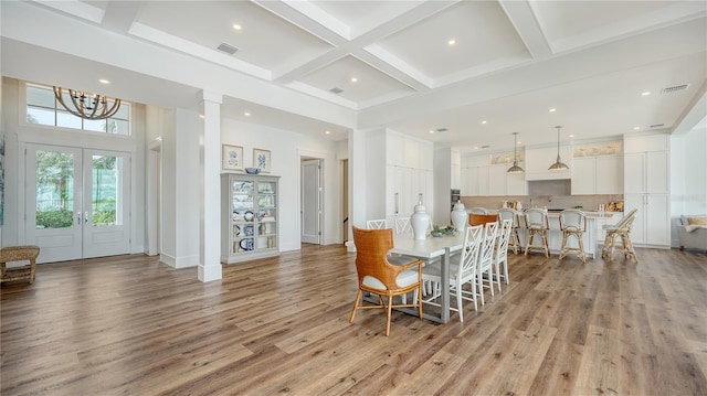 dining area with coffered ceiling, french doors, beamed ceiling, light hardwood / wood-style floors, and a chandelier