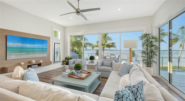 sunroom with ceiling fan and a water view