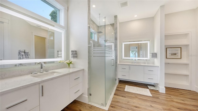 bathroom featuring hardwood / wood-style floors, vanity, and a shower with door