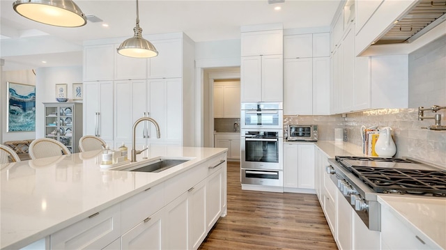 kitchen featuring tasteful backsplash, cooktop, double oven, sink, and white cabinets