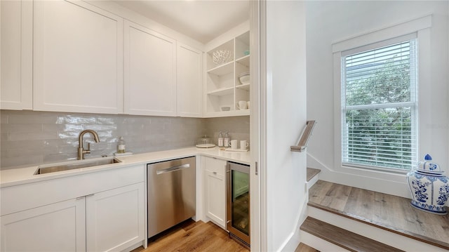 kitchen with dishwasher, sink, light hardwood / wood-style flooring, tasteful backsplash, and white cabinetry