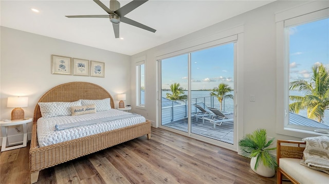 bedroom featuring access to exterior, ceiling fan, a water view, and wood-type flooring