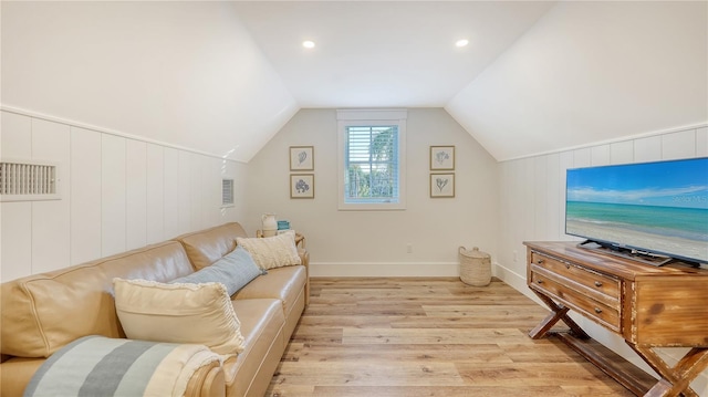 living room featuring light wood-type flooring, vaulted ceiling, and wood walls